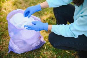 joven hombre recoge basura en un bolsa, trabajar como voluntario foto