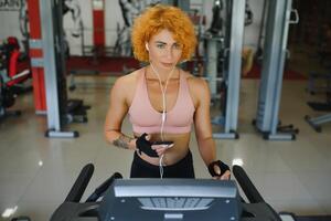 attractive young woman runs on a treadmill, is engaged in fitness sport club photo