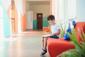 Portrait of a schoolboy standing with a backpack on an empty school hallway. Back to school. photo