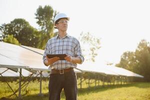 el retrato de un joven ingeniero cheques fotovoltaica solar paneles concepto renovable energía, tecnología, electricidad, servicio, verde fuerza. foto