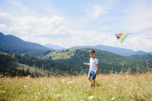 little boy holds string of kite flying in blue sky with clouds in summer with copyspace photo