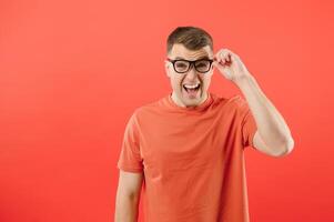 Young handsome man wearing glasses and sweater standing over red background with a happy and cool smile on face. Lucky person. photo