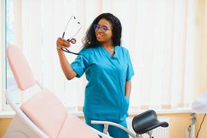 profesional hembra médico en borroso consultante habitación antecedentes. africano americano ginecólogo. ginecología concepto. foto