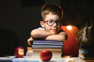 Boy learn lessons in the home setting at the table in the light of a table lamp. photo