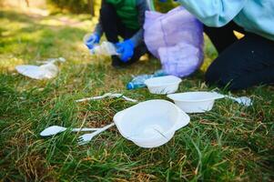 mano pone el plastico escombros en el basura bolso en el parque foto