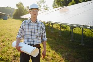 planta de energía solar. hombre parado cerca de paneles solares. energía renovable. foto