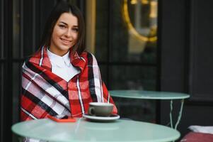 retrato de una joven hermosa mujer sentada en un café al aire libre bebiendo café foto