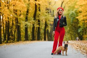 Beautiful and happy woman enjoying in park walking with her adorable French bulldog. photo