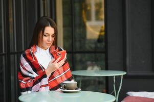 retrato de una joven hermosa mujer sentada en un café al aire libre bebiendo café foto