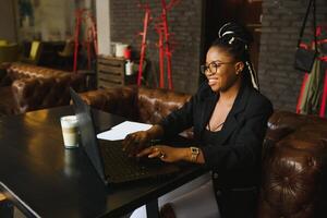 Portrait of a young black woman smiling and using laptop photo