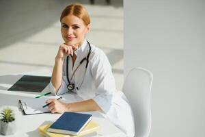 Female doctor working at office desk and smiling, office interior on background photo