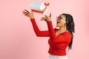 Portrait of pretty cheerful wavy-haired girl holding in hands giftbox congrats sale copy space isolated over pink pastel color background. photo