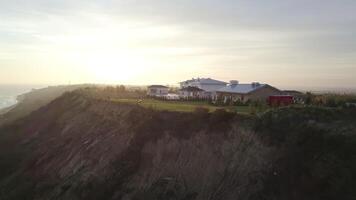 un grande casa en el borde de un acantilado por el Oceano a amanecer video