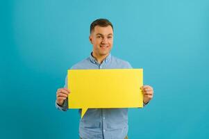 guy holding speech bubble on blue studio background, mockup for design photo