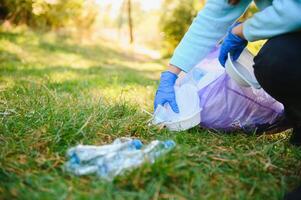 Young man collects garbage in a bag, volunteering photo