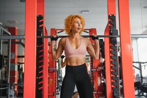 Beautiful girl exercising squatting with barbell photo