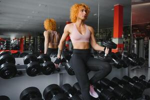 Close up of sporty woman lifting dumbbell in gym. photo