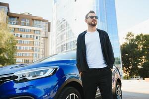 hermoso joven hombre en en pie cerca coche al aire libre foto