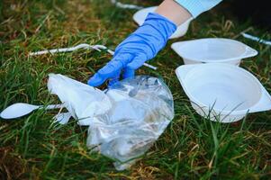 hand puts plastic debris in the garbage bag in the park photo