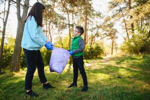 joven hombre recoge basura en un bolsa, trabajar como voluntario foto