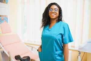 Young african american female doctor gynecologist standing in clinic office. photo