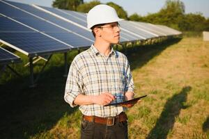 Inspector Engineer Man Holding Digital Tablet Working in Solar Panels Power Farm, Photovoltaic Cell Park, Green Energy Concept photo