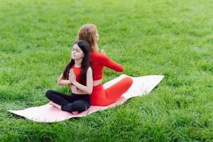 Mother practicing yoga with her daughter in the open air. photo