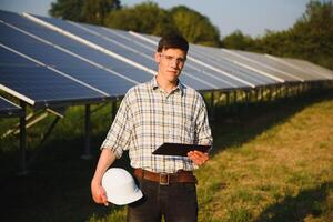 Inspector Engineer Man Holding Digital Tablet Working in Solar Panels Power Farm, Photovoltaic Cell Park, Green Energy Concept photo