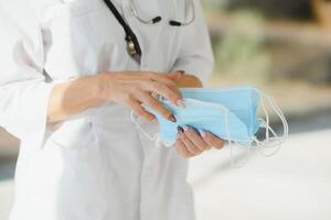 Beautiful doctor holding protective mask in hand, happy to end quarantine. copy space, white background photo