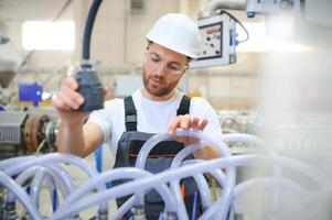 A male worker in a special uniform and an white helmet. Production of frames for PVC windows photo