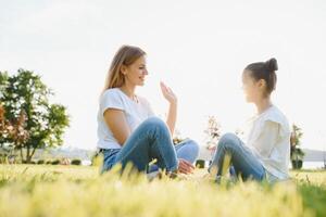 Mother and daughter having fun in the park. Happy family concept. Beauty nature scene with family outdoor lifestyle. Happy family resting together. Happiness and harmony in family life. photo