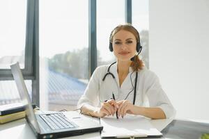 joven hembra médico hablando a paciente en línea desde médico oficina. médico consultante cliente en vídeo charla ordenador portátil a hospital. foto
