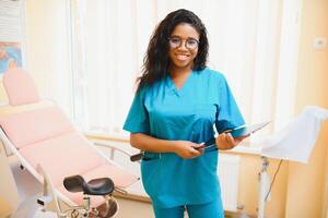 joven africano americano hembra médico ginecólogo en pie en clínica oficina. foto