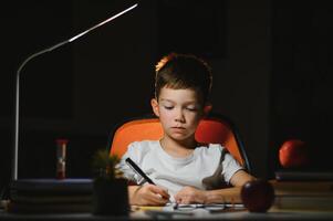 schoolboy doing homework at the table in his room. photo