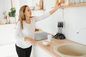 Pregnant woman in kitchen making salad photo