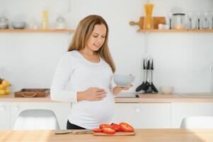 embarazada mujer en cocina haciendo ensalada foto