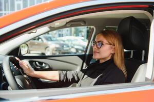 hermosa maduro mujer en negocio traje conducción un coche a oficina. mujer de negocios conducir un coche en ciudad. foto