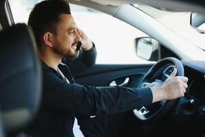 Test drive for auto. Pleasant overjoyed handsome boy holding steering wheel and driving his car while expressing gladness photo