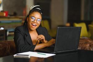 Portrait of a young black woman smiling and using laptop photo