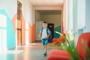 retrato de un colegial en pie con un mochila en un vacío colegio pasillo. espalda a escuela. foto