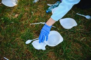 hand puts plastic debris in the garbage bag in the park photo