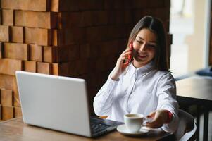 Cute girl freelancer smiling and working with laptop in stylish cafe photo