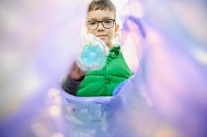 boy throws plastic trash in a bag in the park photo