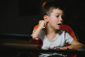 Boy learn lessons in the home setting at the table in the light of a table lamp. photo