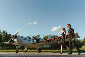 Portrait of two smiling business people, man and woman, walking by plane hangar in airport field photo