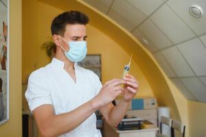 male doctor holds syringe while standing in the patient room photo