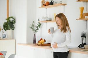 hermosa embarazada mujer bebidas té o café. interior foto. foto