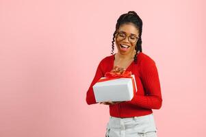 foto retrato de emocionado mujer participación regalo caja en dos manos aislado en pastel rosado de colores antecedentes.