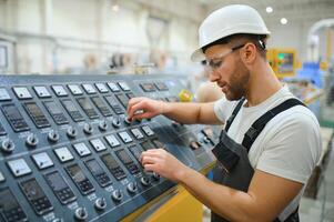 Smiling and happy employee. Industrial worker indoors in factory. Young technician with hard hat photo