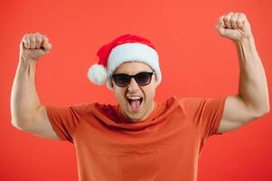 retrato de contento y emocionado hombre en Papa Noel sombrero, alegría y victorioso algo, celebrando nuevo año, en pie terminado rojo antecedentes foto